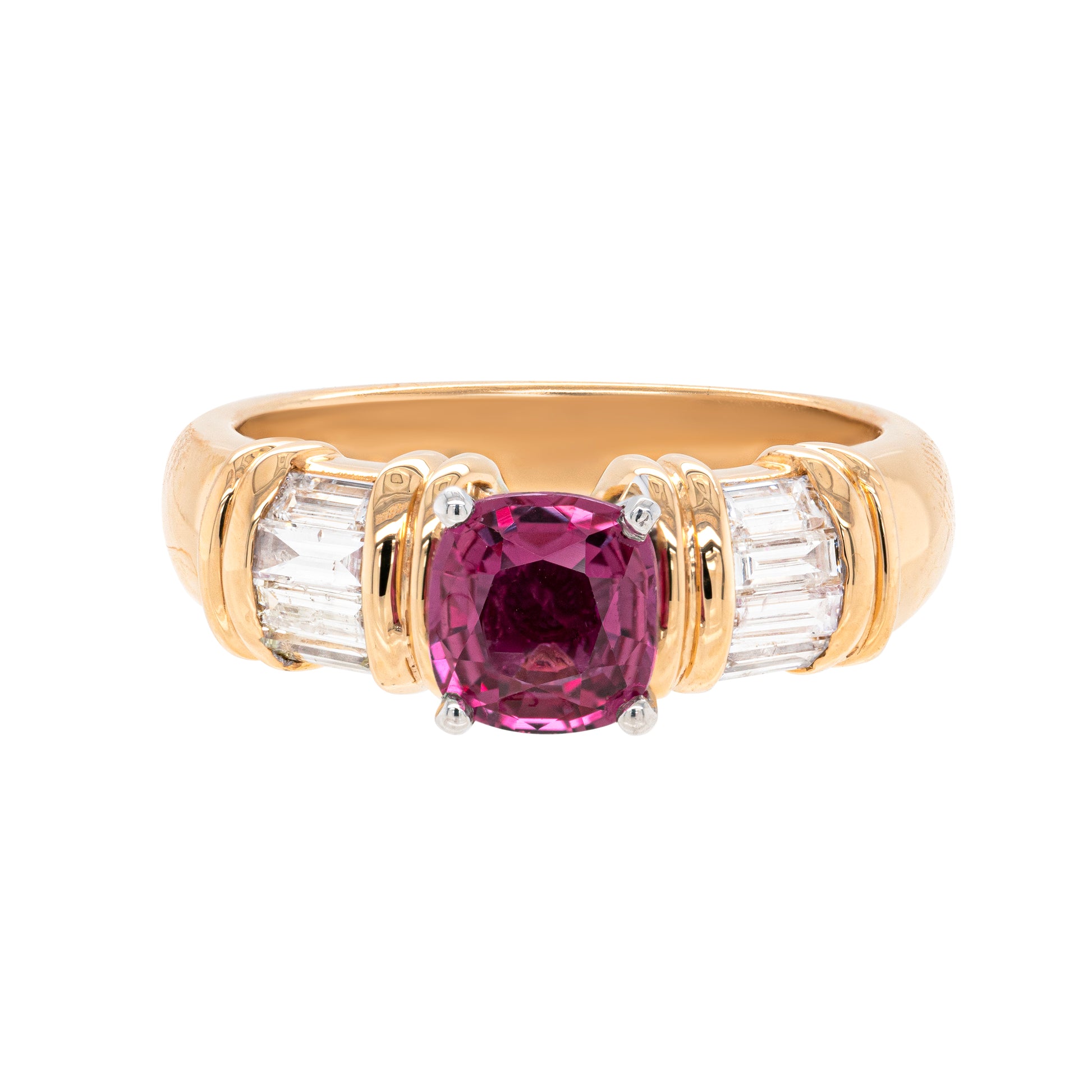 An 18 carat yellow gold ring with a cushion shaped pink sapphire in the centre and four channel set baguette cut diamonds on either side.