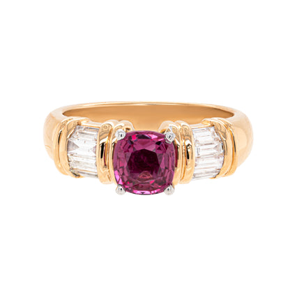 An 18 carat yellow gold ring with a cushion shaped pink sapphire in the centre and four channel set baguette cut diamonds on either side.