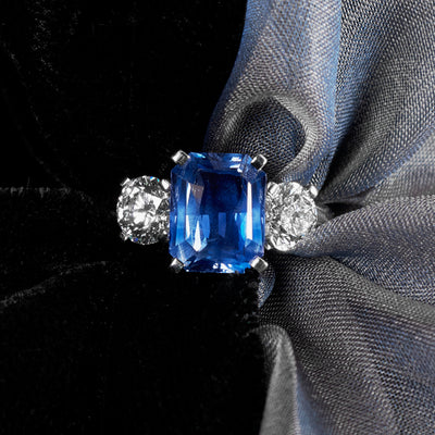 Ring with a blue sapphire and diamond accents on a black and gray fabric background
